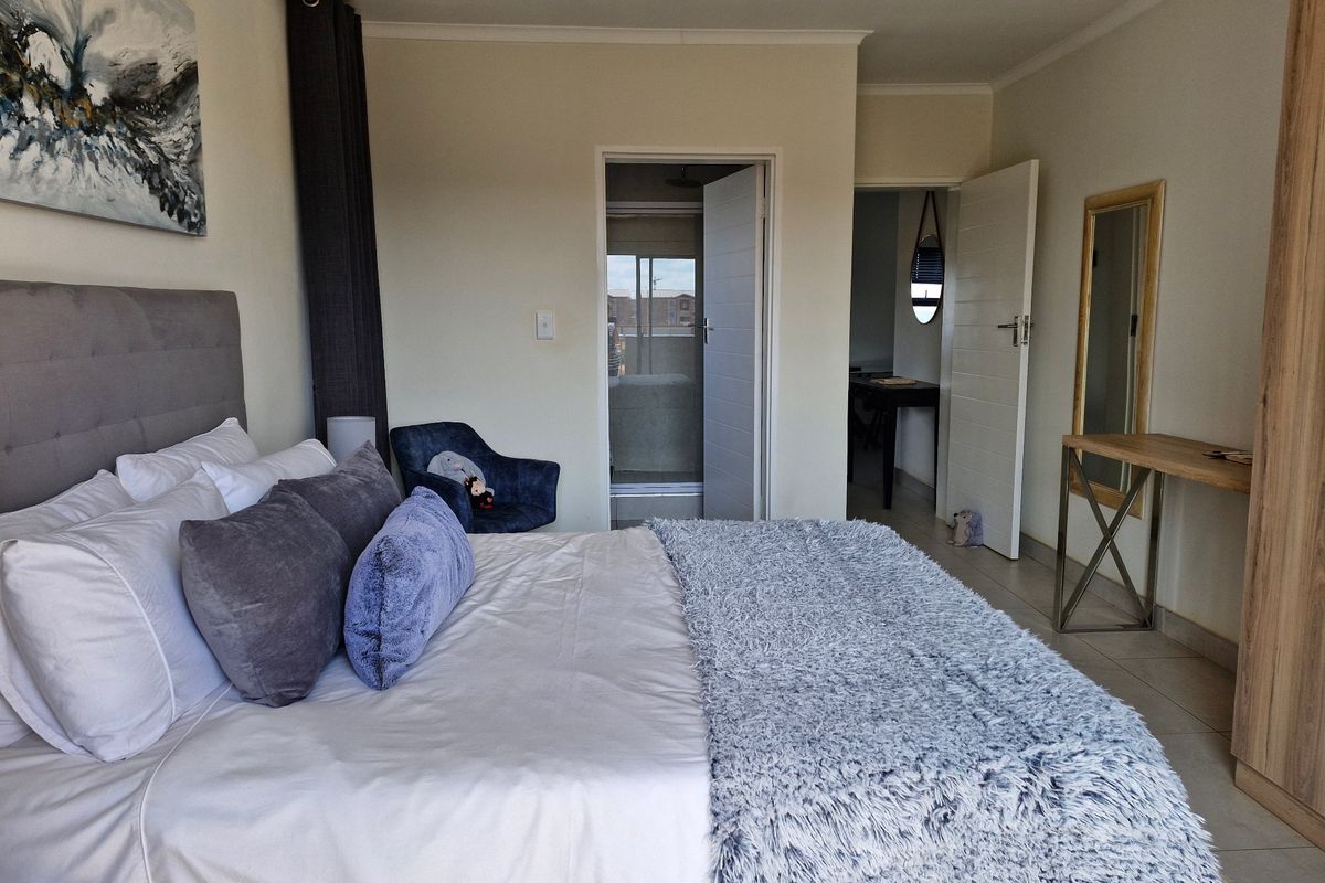A well-maintained bedroom featuring tiled flooring, a built-in wardrobe, and direct access to an en-suite bathroom.
