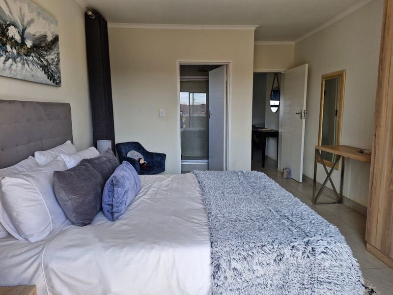 A well-maintained bedroom featuring tiled flooring, a built-in wardrobe, and direct access to an en-suite bathroom.