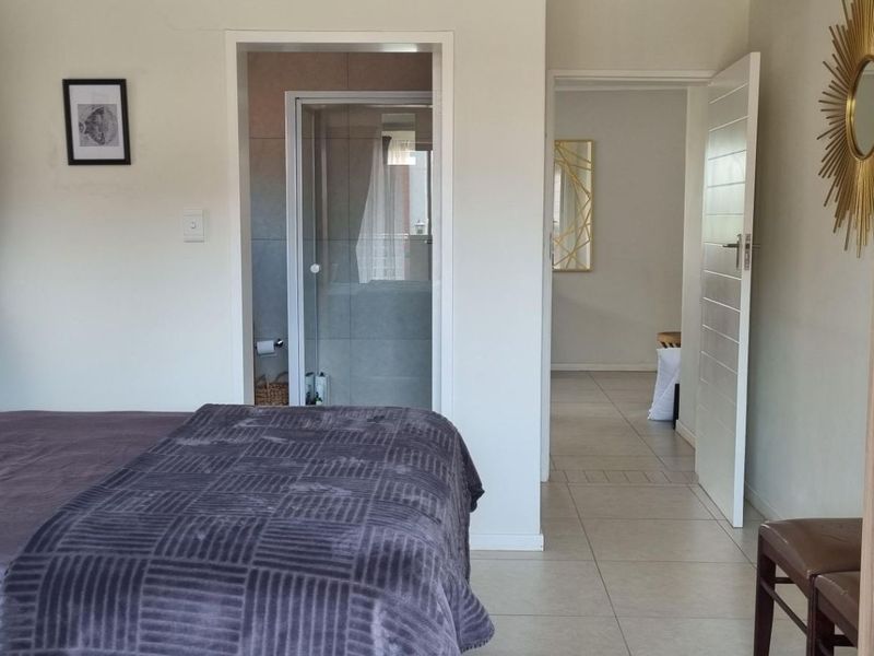 A well-maintained bedroom featuring tiled flooring, a built-in wardrobe, and direct access to an en-suite bathroom.