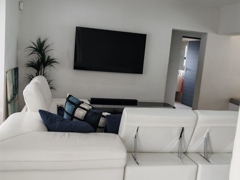 A modern living room featuring recessed downlighting and a neutral interior finish, providing a clean and contemporary space.