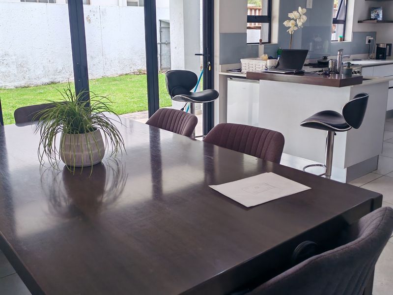 Open-plan dining and kitchen area featuring a central island, modern cabinetry, and large sliding doors providing seamless access to the garden.