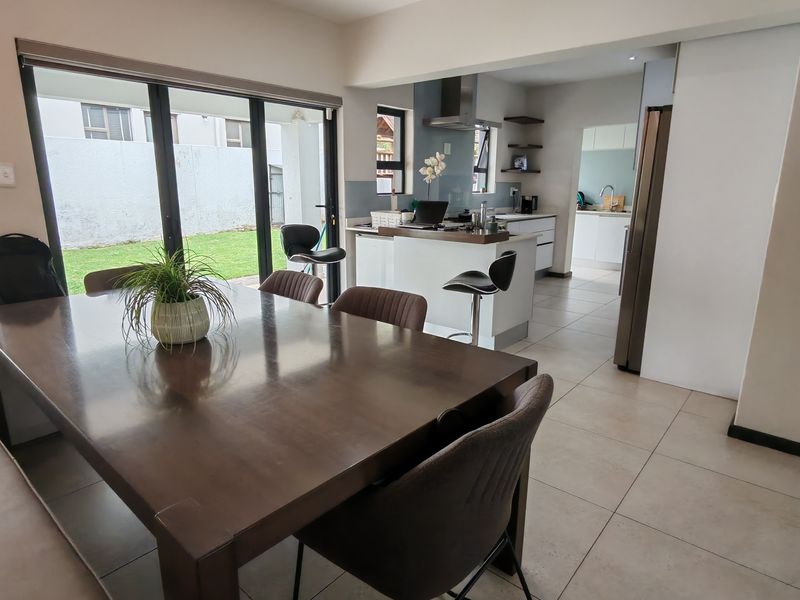 Open plan dining and kitchen area featuring tiled floors, modern cabinetry, and large sliding glass doors providing seamless access to the rear garden.