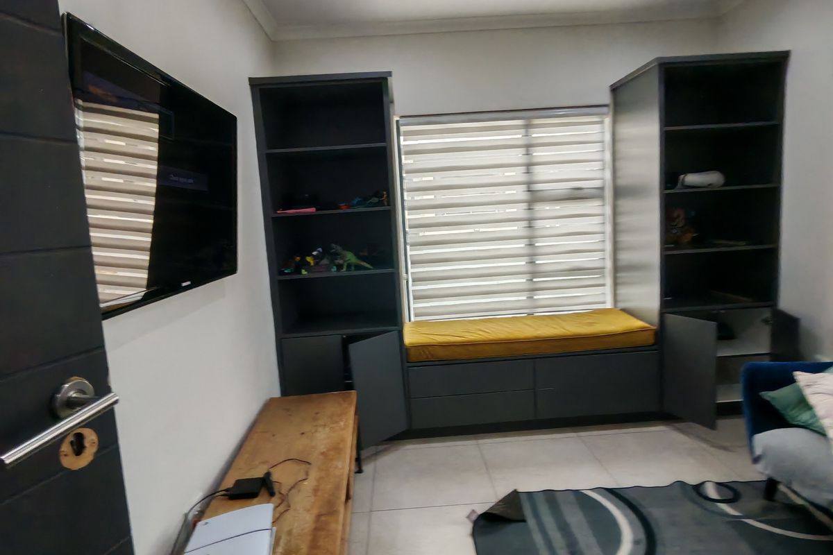 Bedroom featuring built-in dark cabinetry with integrated shelving and a window seat, complemented by tiled flooring and recessed lighting.