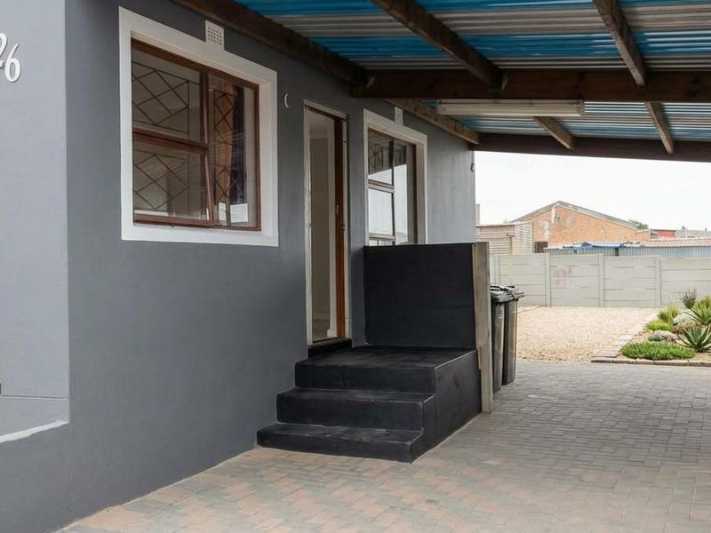 Front exterior view featuring a paved driveway, covered carport, and secure entrance with security bars on windows.