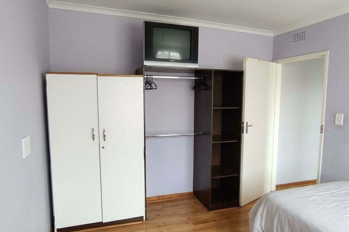 Bedroom featuring laminate flooring and a built-in wardrobe with integrated shelving and hanging space.