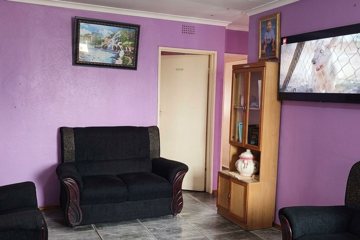 A living room featuring tiled flooring and coved ceilings, currently finished with purple wall paint.