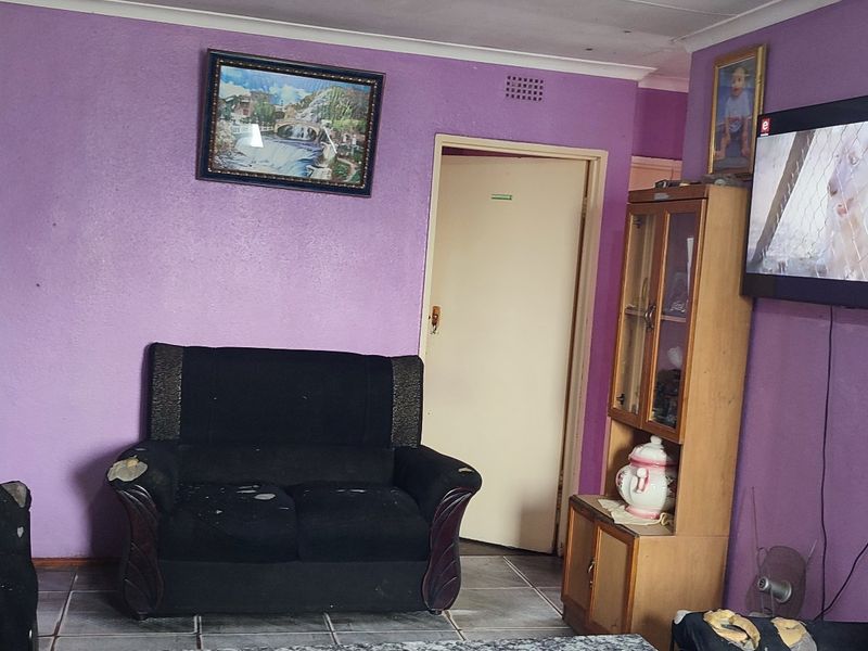 A living room featuring tiled flooring and coved ceilings, currently requiring cosmetic updates to the wall finishes.