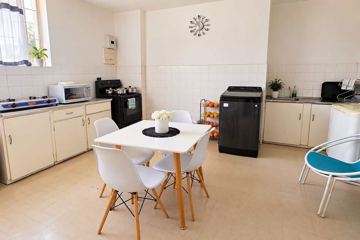 A functional kitchen featuring built-in cabinetry, tiled splashbacks, and a stainless steel sink, offering a practical layout with space for dining.
