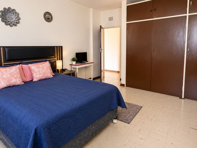 A bedroom featuring built-in cupboards and tiled flooring, offering a functional space with potential for cosmetic updates.