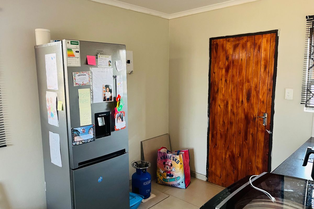 A functional kitchen area featuring tiled flooring and a solid wooden door, providing a practical space for daily meal preparation.