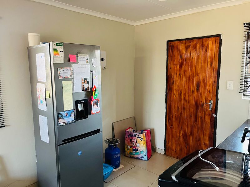 A functional kitchen area featuring tiled flooring and a solid wooden door, providing a practical space for daily meal preparation.