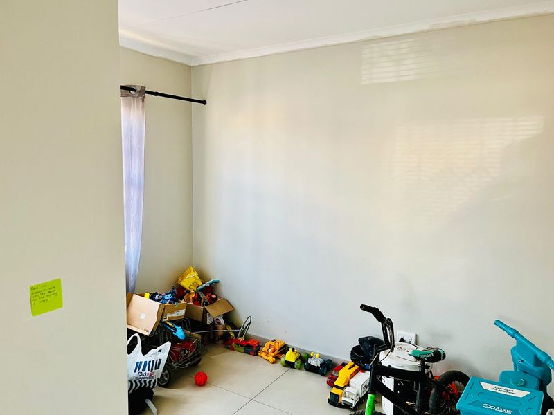A bedroom space featuring neutral wall paint, tiled flooring, and a curtain rod, providing a blank canvas for potential interior design updates.