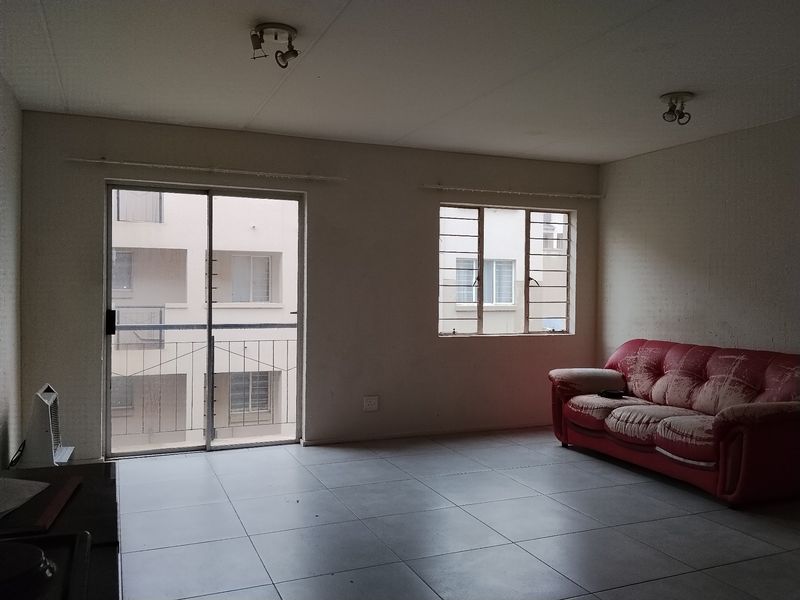 A living room featuring tiled flooring, a sliding glass door with security bars, and ceiling-mounted lighting, offering a blank canvas for renovation.