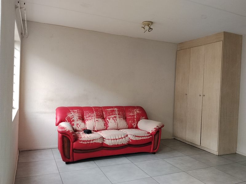 A bedroom featuring tiled flooring, a built-in wardrobe, and a louvered window, providing a functional space with potential for cosmetic updates.