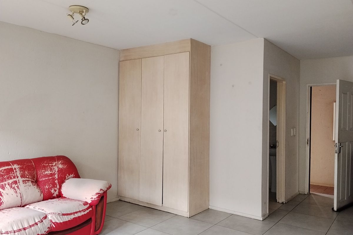 Bedroom featuring tiled flooring, a built-in wardrobe, and access to an adjoining bathroom area.