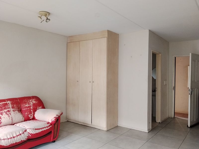 Bedroom featuring tiled flooring, a built-in wardrobe, and access to an adjoining bathroom area.