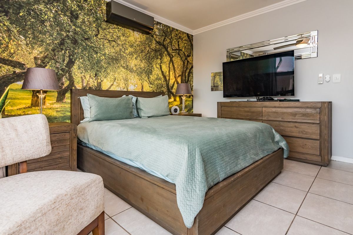 A well-maintained bedroom featuring tiled flooring, crown molding, and a wall-mounted air conditioning unit.