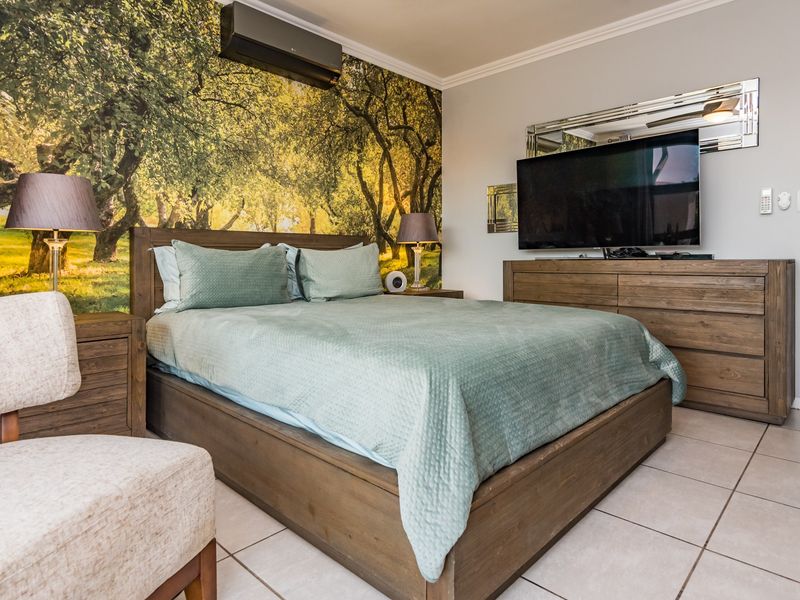 A well-maintained bedroom featuring tiled flooring, crown molding, and a wall-mounted air conditioning unit.