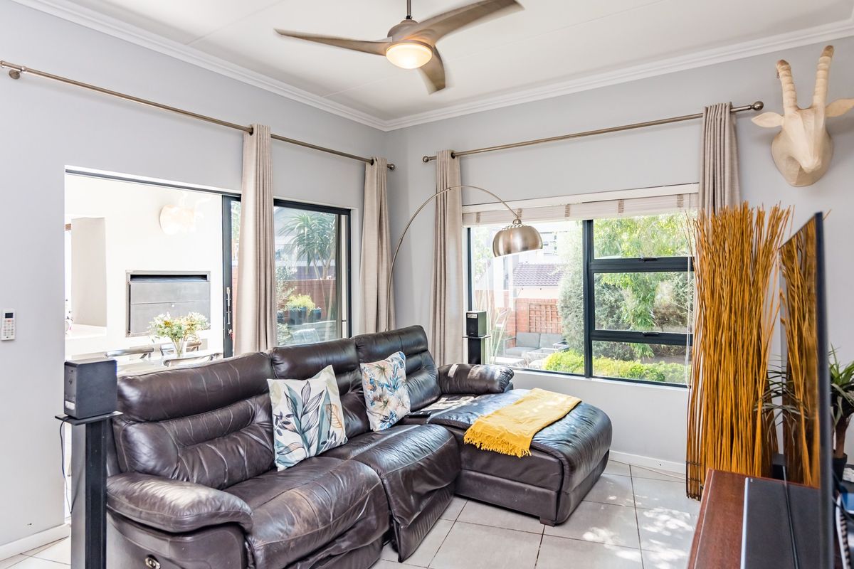 A bright living room featuring tiled flooring, a ceiling fan, and large sliding glass doors that provide natural light and access to the patio area.