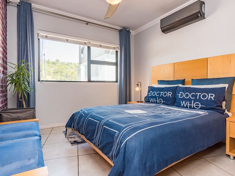 A well-maintained bedroom featuring tiled flooring, a ceiling fan, and a wall-mounted split-system air conditioner.