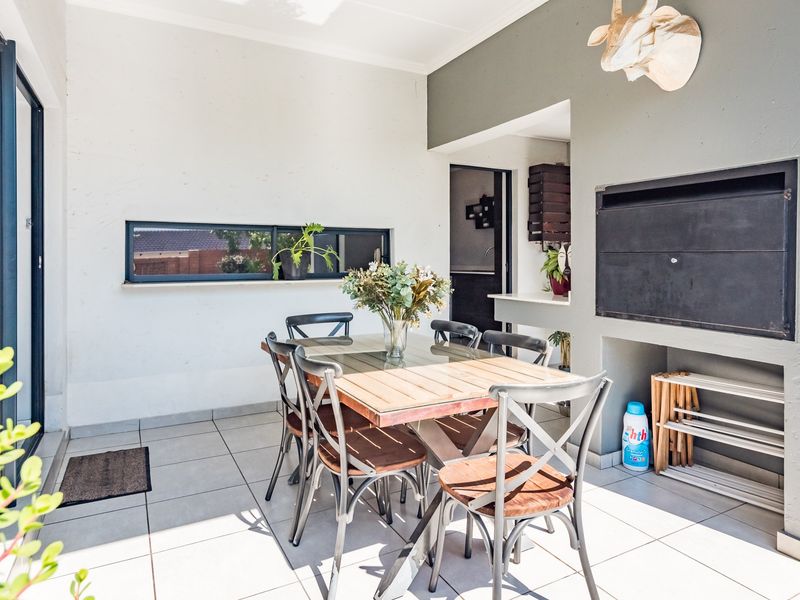 A covered patio area featuring tiled flooring, a built-in braai, and a sliding door providing access to the interior.