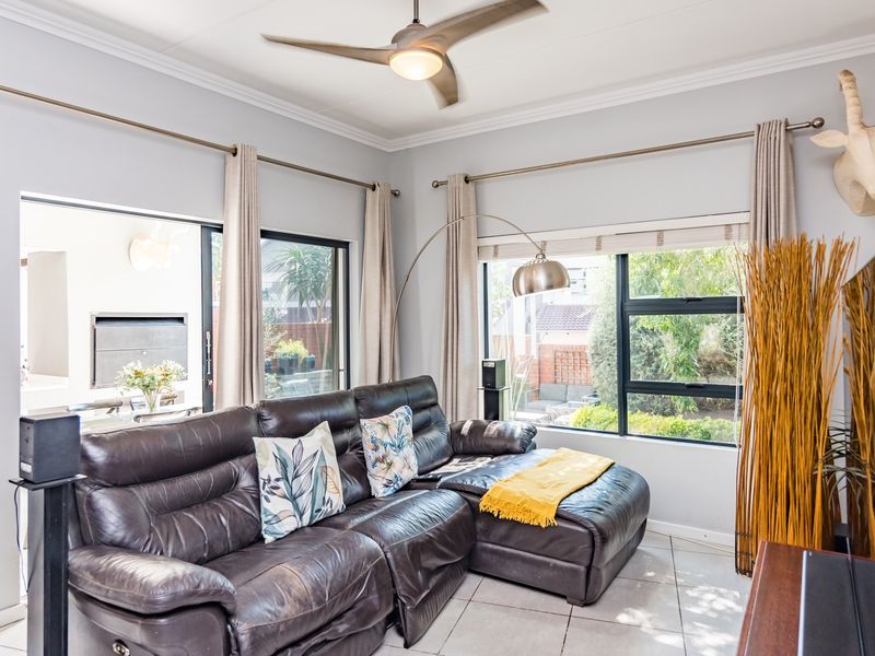 A bright living room featuring tiled flooring, a ceiling fan, and large sliding glass doors that provide natural light and access to the patio area.