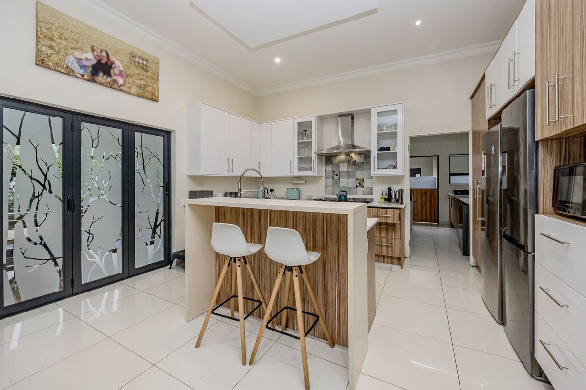Modern kitchen featuring a central island, built-in cabinetry, tiled backsplash, and sleek tiled flooring, with direct access to an outdoor area.
