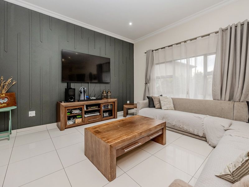 A well-maintained living room featuring a modern dark grey feature wall, large format floor tiles, and recessed lighting.