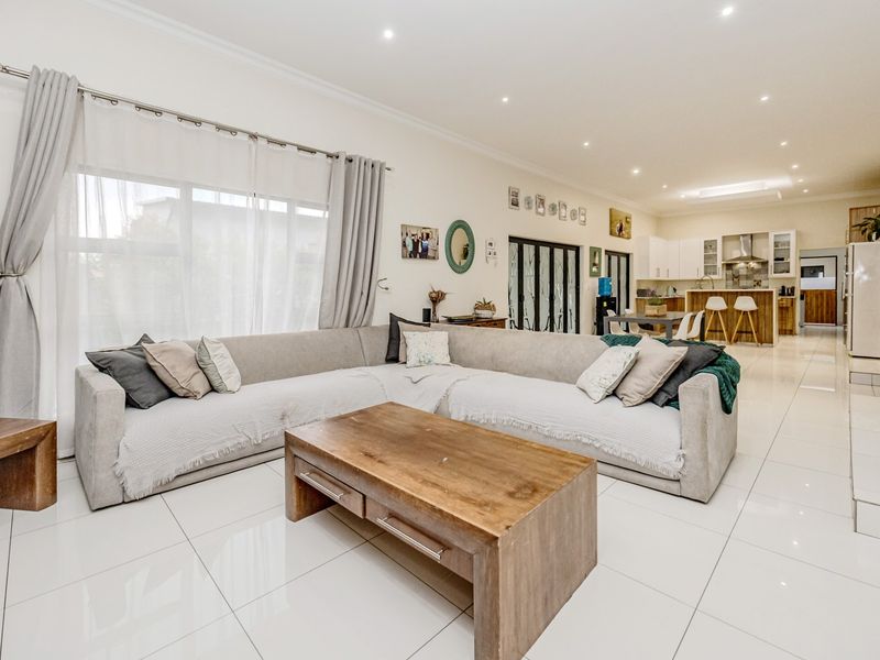Spacious open-plan living area featuring polished porcelain floor tiles, recessed lighting, and a modern kitchen with integrated cabinetry and island.