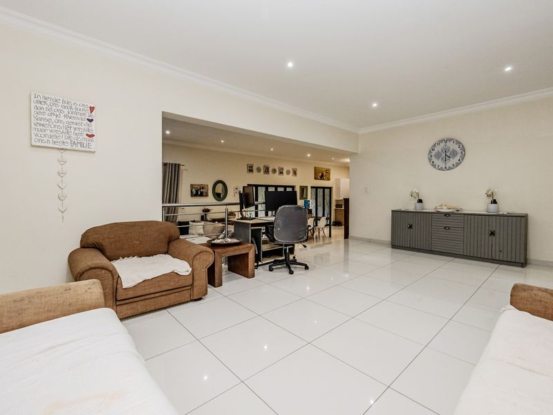 Spacious open-plan living area featuring polished porcelain floor tiles, recessed downlighting, and a modern metal balustrade overlooking the adjacent lower-level space.