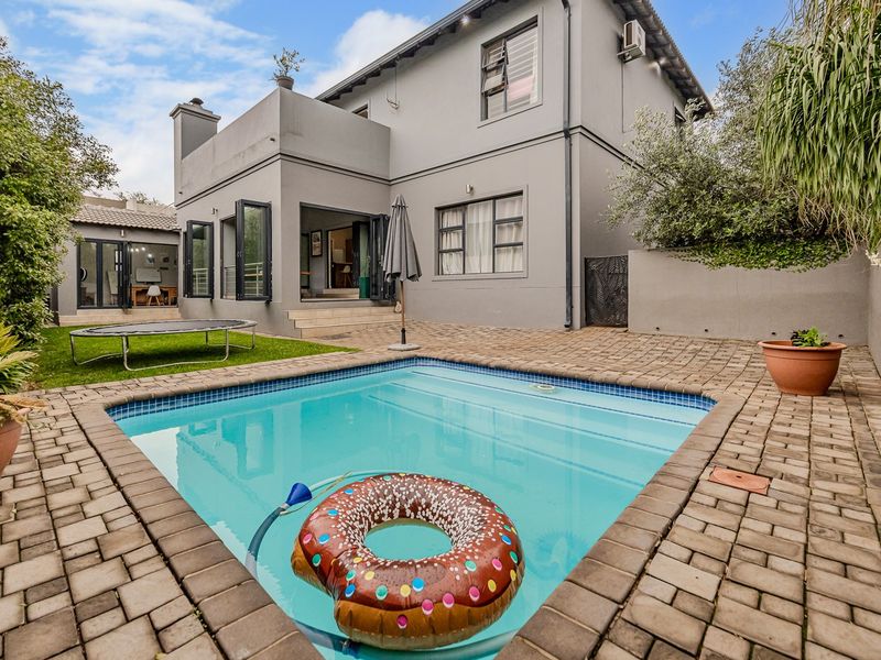Rear exterior view featuring a swimming pool, paved patio area, and direct access to the home through bi-fold doors.