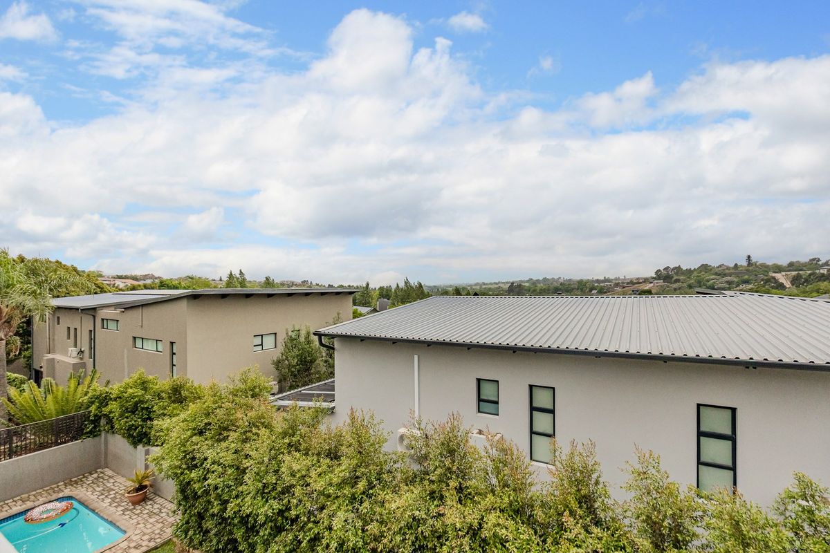 Aerial view of a modern residential property featuring metal roofing, a swimming pool, and landscaped garden areas.