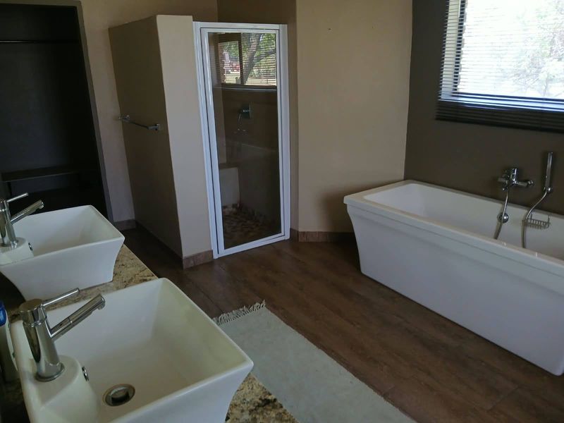 Spacious bathroom featuring a double vanity, a modern freestanding bathtub, and a separate shower enclosure with wood-look laminate flooring.