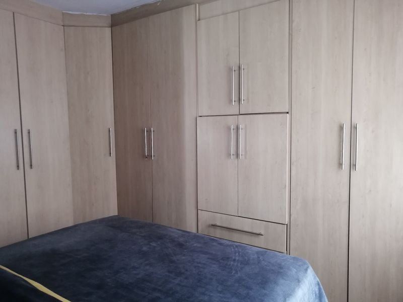 A bedroom featuring extensive light-toned built-in cupboards providing ample storage space.
