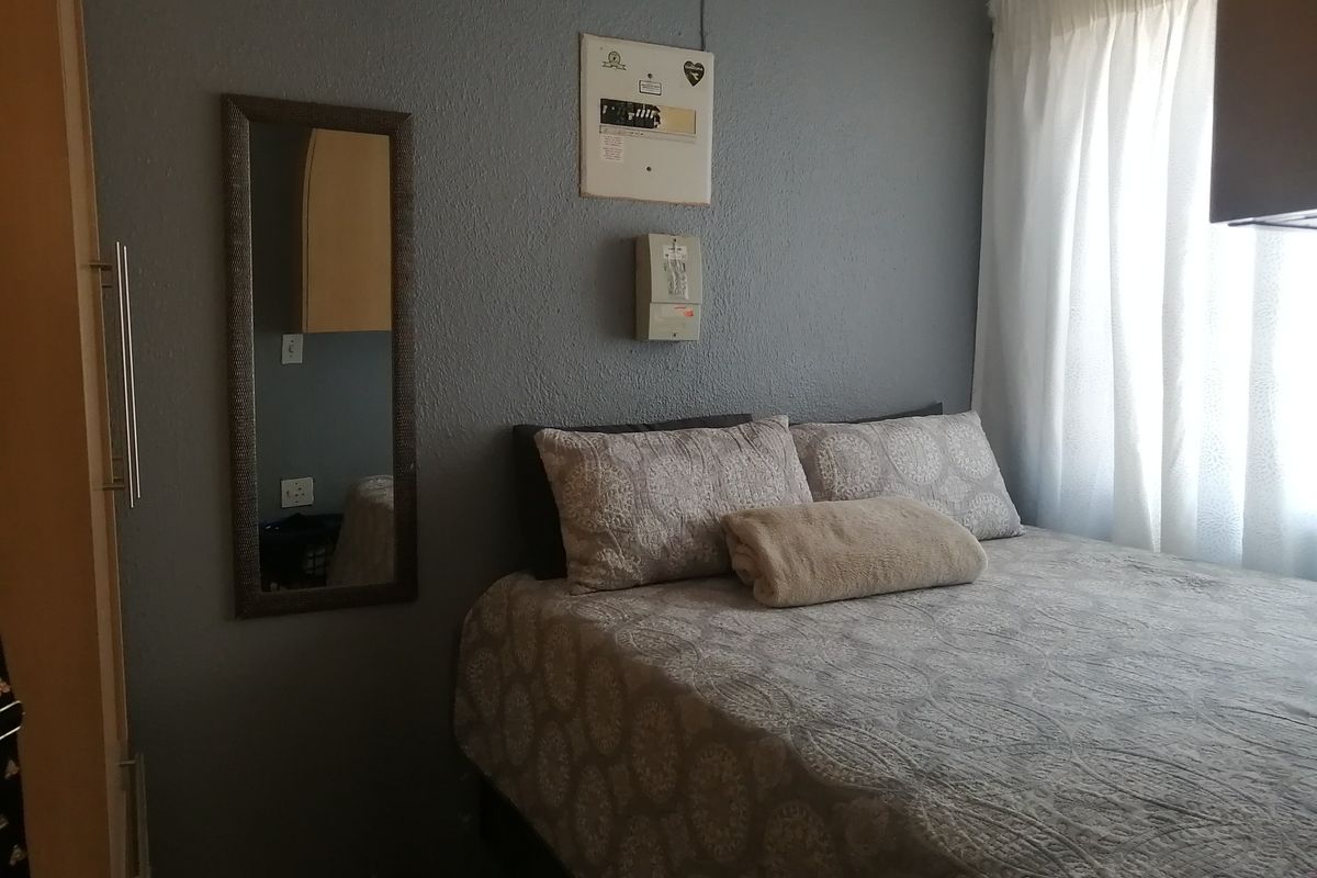 A bedroom featuring a built-in wardrobe, curtain rails, and a wall-mounted electrical distribution board.