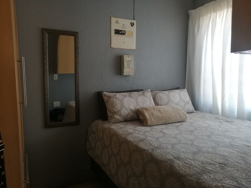 A bedroom featuring a built-in wardrobe, curtain rails, and a wall-mounted electrical distribution board.