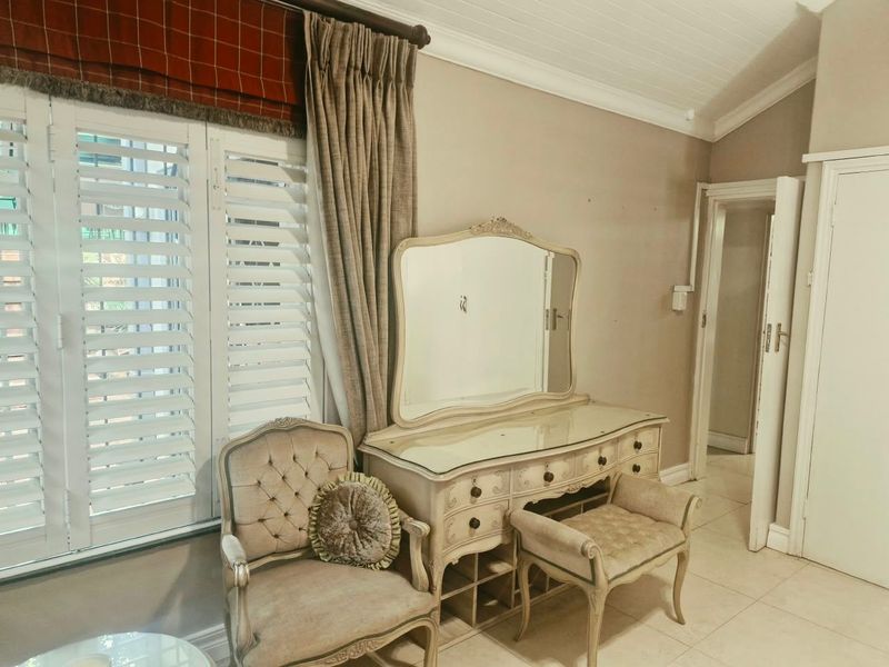 A bedroom featuring tiled flooring, vaulted ceilings, and white plantation shutters, providing a bright and neutral space.