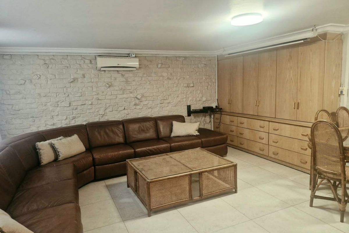 Spacious living area featuring a stone veneer accent wall, integrated floor-to-ceiling wooden cabinetry, and a wall-mounted air conditioning unit.