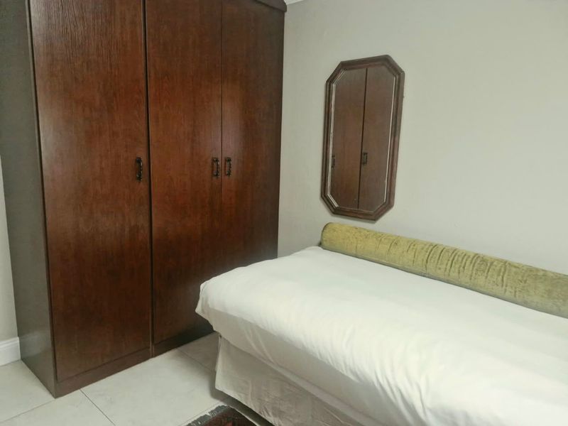 A bedroom featuring a large built-in wooden wardrobe and neutral wall finishes.