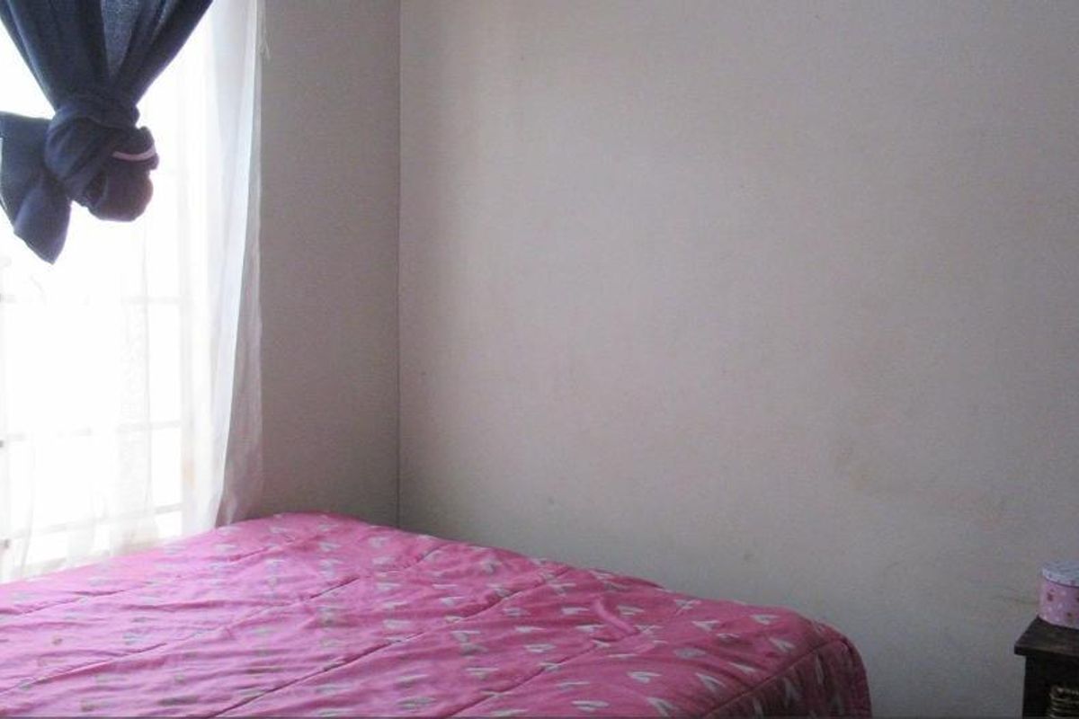 A simple bedroom featuring a window with natural light and plain wall finishes.