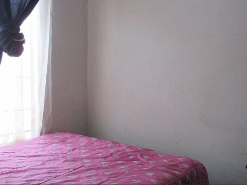 A simple bedroom featuring a window with natural light and plain wall finishes.