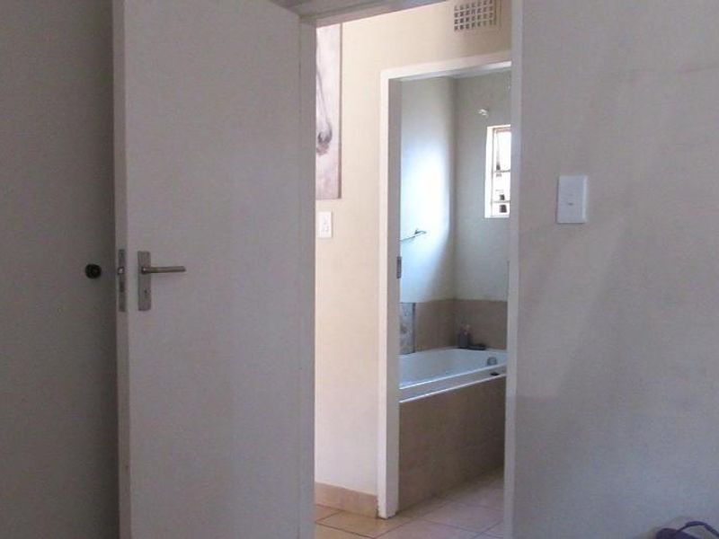 A view through an open doorway looking into a bathroom featuring a built-in bathtub and tiled flooring.