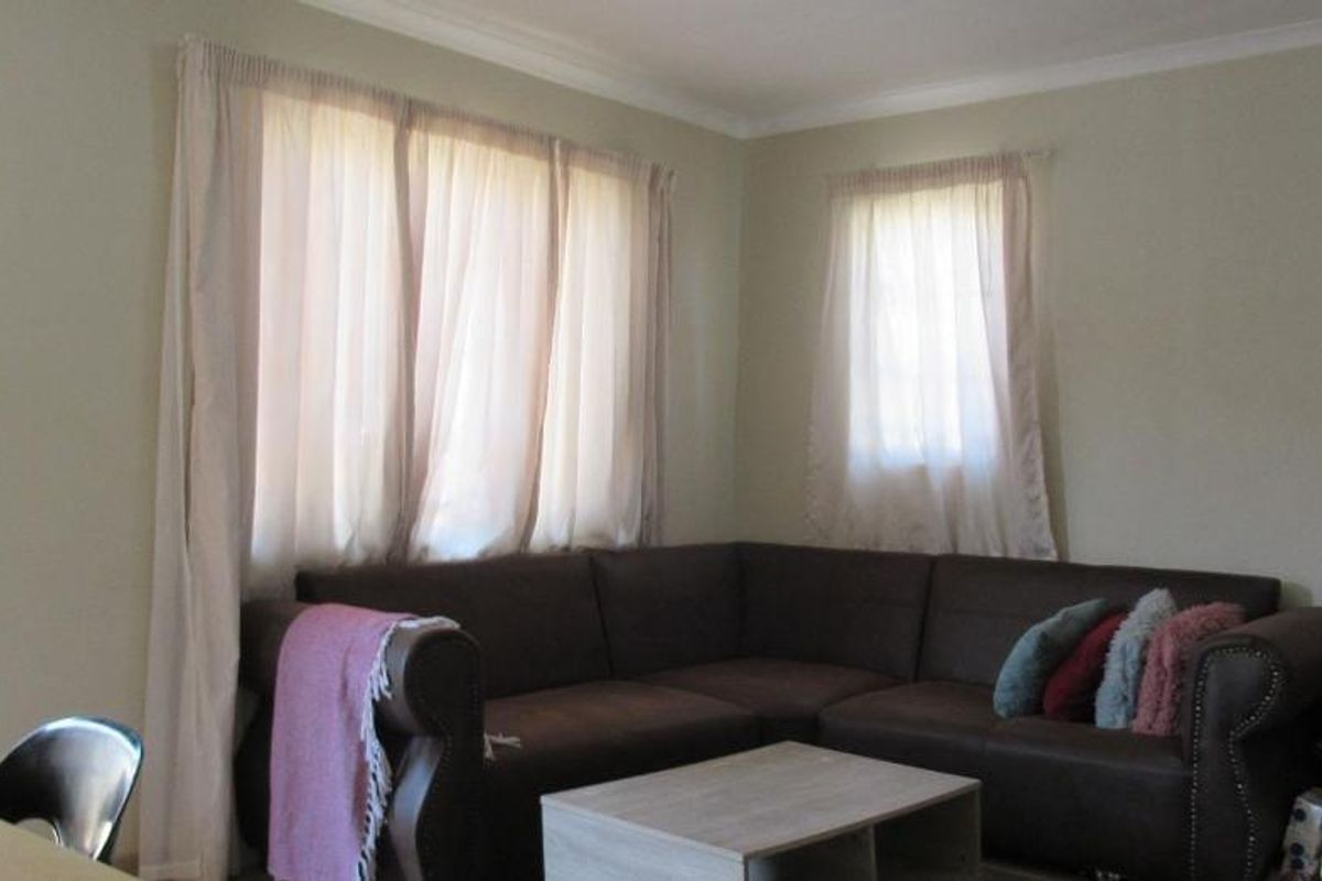A living room area featuring neutral wall tones, cornice detailing, and natural light through window treatments.