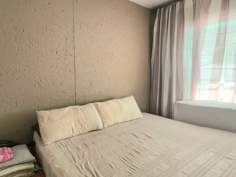 A bedroom featuring textured walls and large windows with curtain tracks, requiring cosmetic updates to improve the overall aesthetic.