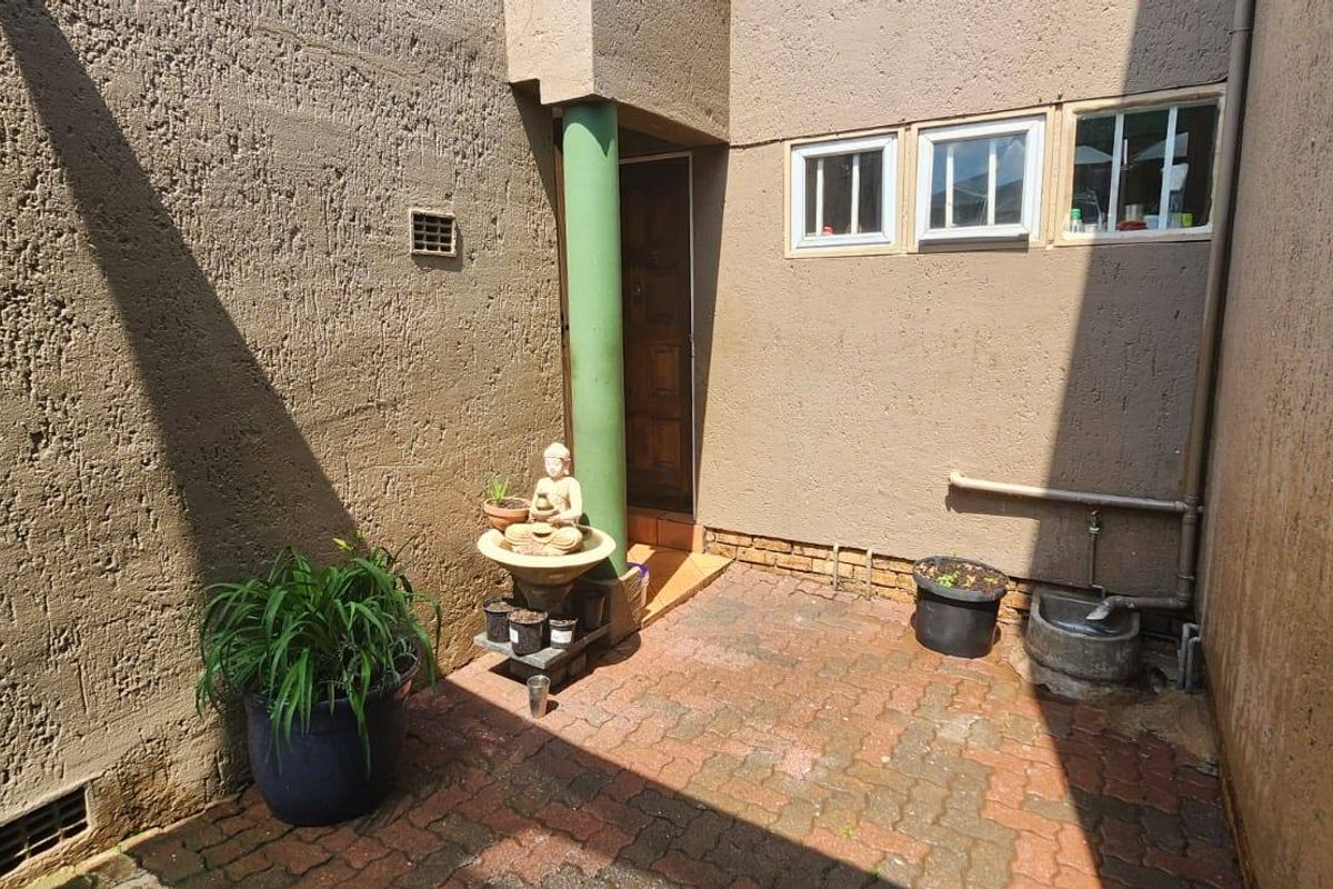 A private paved courtyard area featuring textured exterior walls, a structural column, and access to the main dwelling via a standard door.
