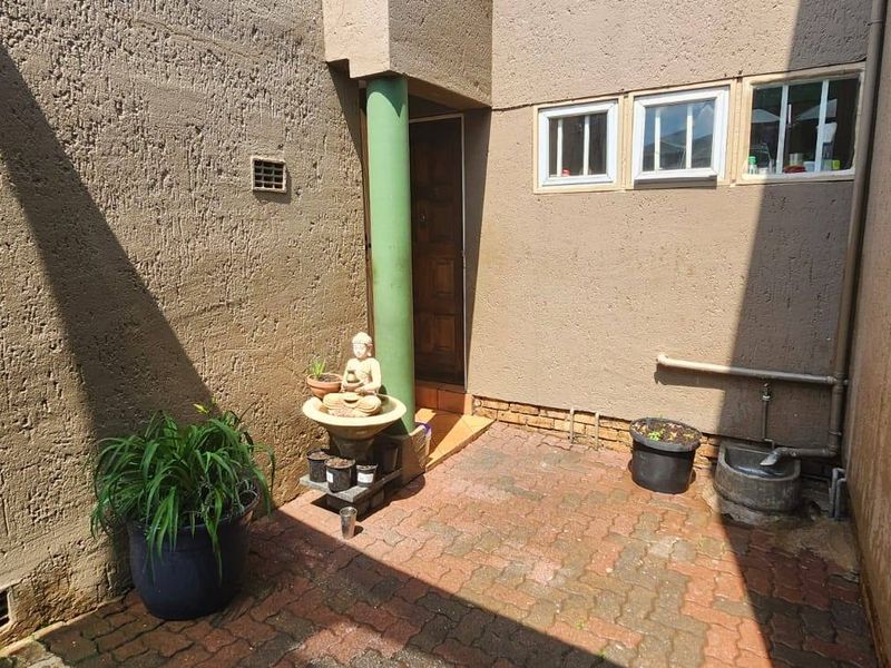 A private paved courtyard area featuring textured exterior walls, a structural column, and access to the main dwelling via a standard door.