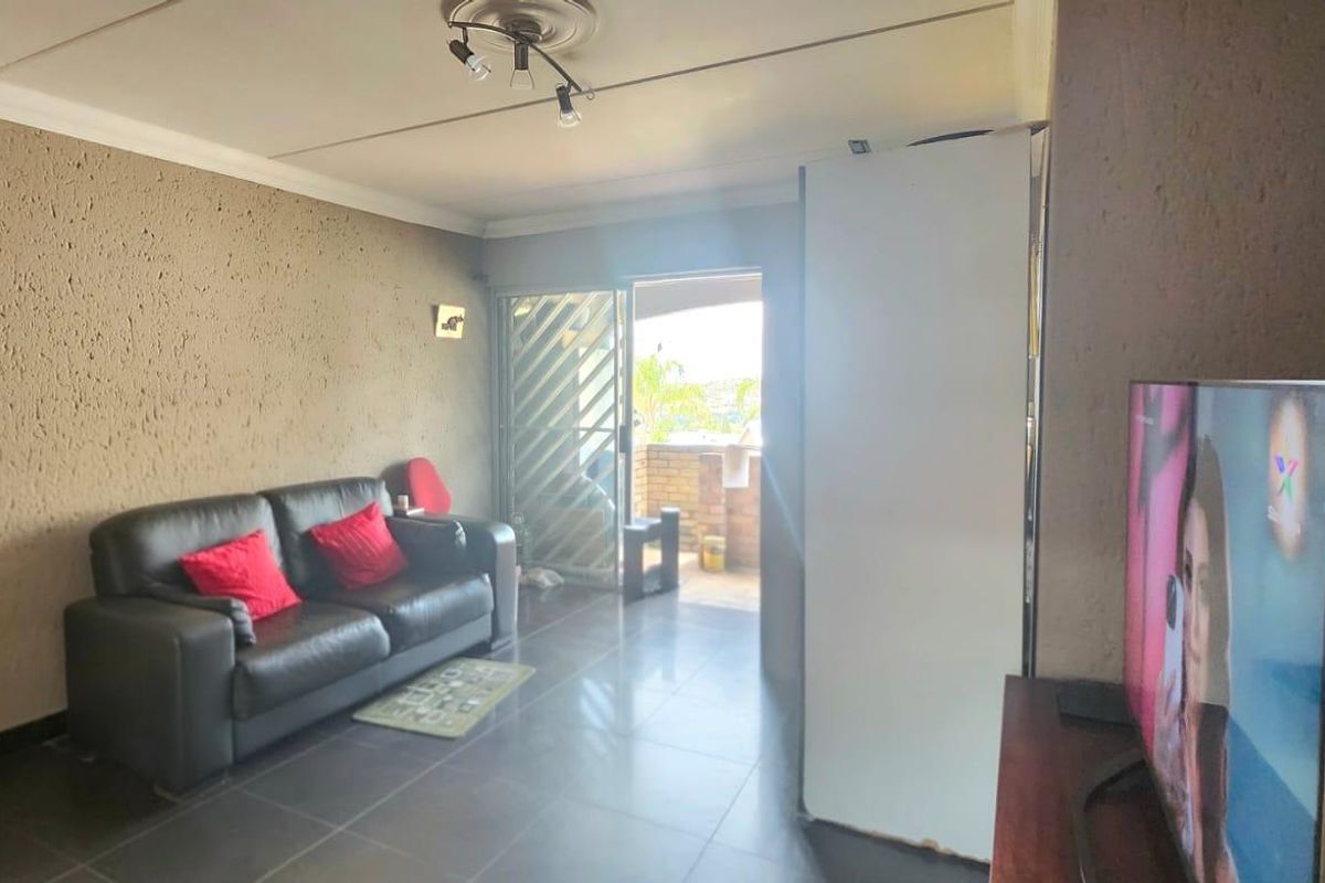 A living room featuring tiled flooring, textured walls, and a sliding glass door providing access to an outdoor area.