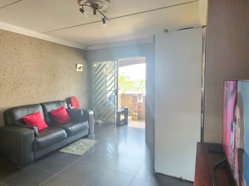 A living room featuring tiled flooring, textured walls, and a sliding glass door providing access to an outdoor area.