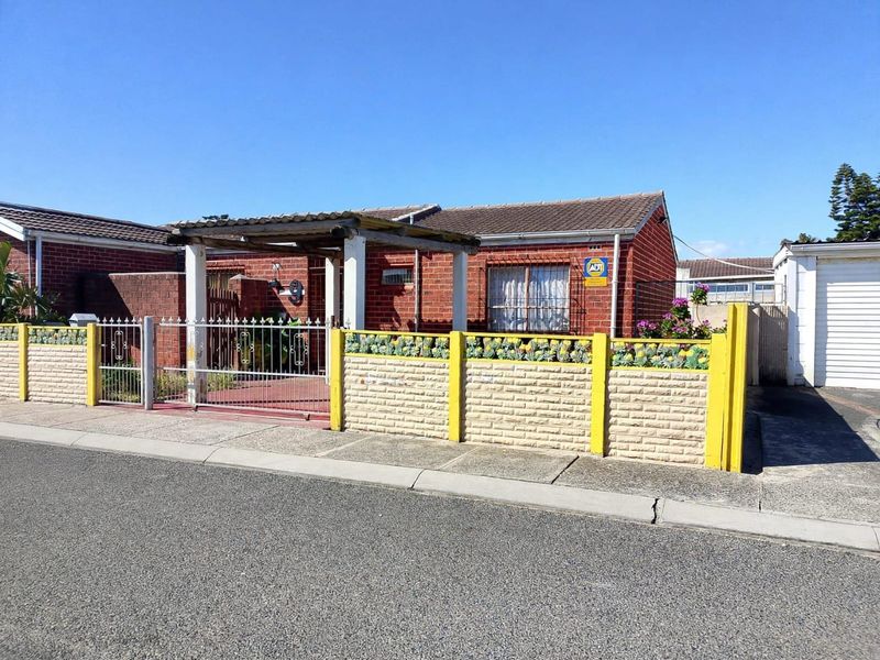 Front view of a face brick house featuring a tiled roof, a covered pergola entrance, and a secure boundary wall with metal gate.