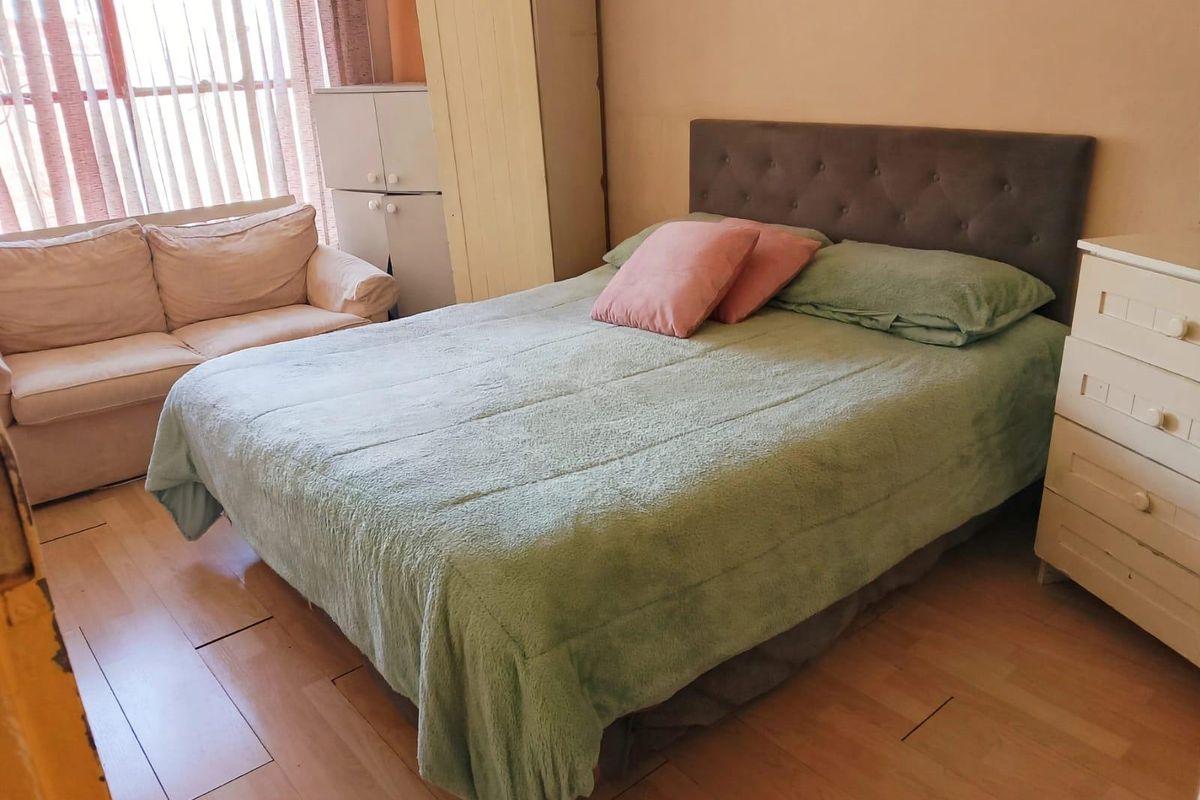 A bedroom featuring laminate flooring and a built-in wardrobe, offering a functional space with natural light from the window.